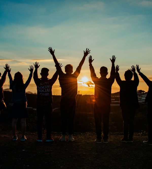 People raising their arms in front of the sunset: This image represents Quartier 35 as a retreat location in Gaindorf in Austria's Weinviertel.